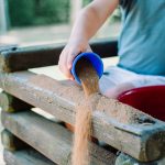 Small child pouring sand from a cup